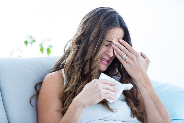 Mujer enferma llorando en el sofá