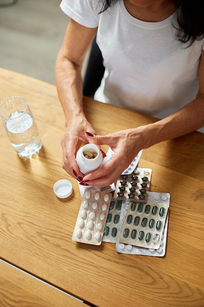 Foto mujer enferma madura que tiene píldoras de aspirina antibiótica de la botella del resfriado de la gripe o el concepto de tratamiento y atención médica del virus estacional