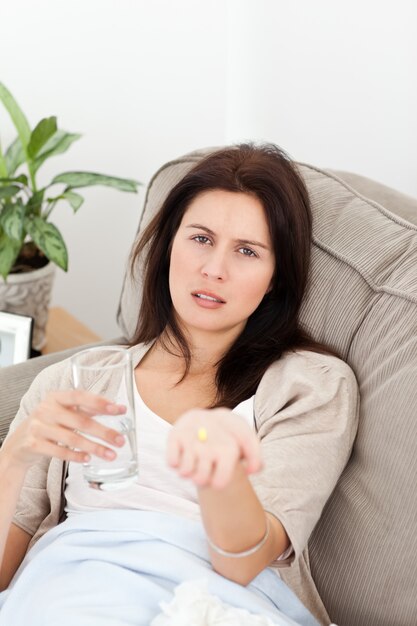 Mujer enferma mostrando una pastilla a la cámara