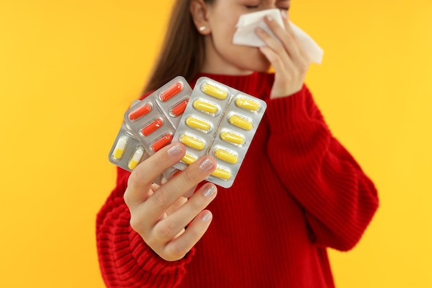 Foto mujer enferma con pastillas sobre fondo amarillo