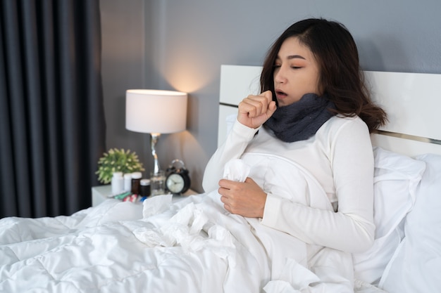 Mujer enferma siente frío y tos en la cama
