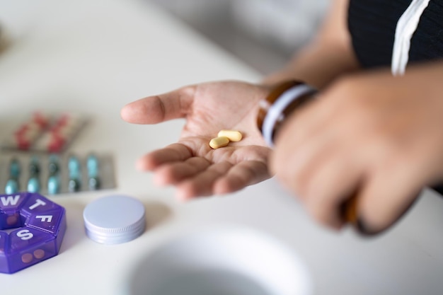 Foto la mujer enferma sostiene dos pastillas en la mano vertiendo cápsulas de la botella de medicamentos toma analgésicos suplementos de medicina cuidado de la salud concepto de terapia de tratamiento de dolor de cabeza