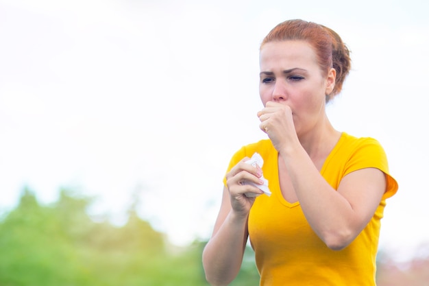 Mujer enferma tosiendo al aire libre. La mujer durante una epidemia de gripe y resfriado sufre de bronquitis o alergias.