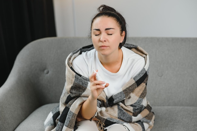 Mujer enferma usando spray nasal en casa