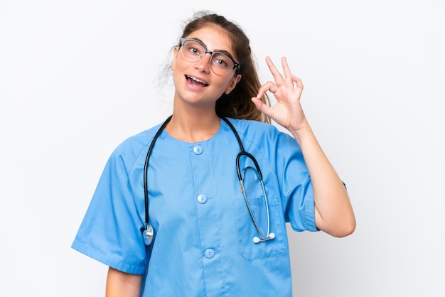 Mujer enfermera médica joven aislada en fondo blanco mostrando el signo ok con los dedos