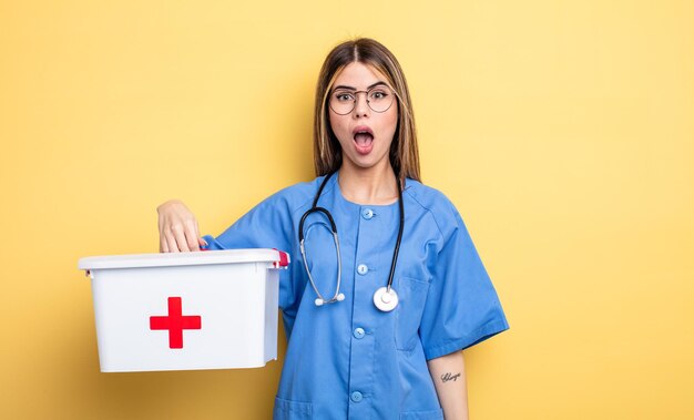 Mujer enfermera que parece muy sorprendida o sorprendida. concepto de botiquín de primeros auxilios