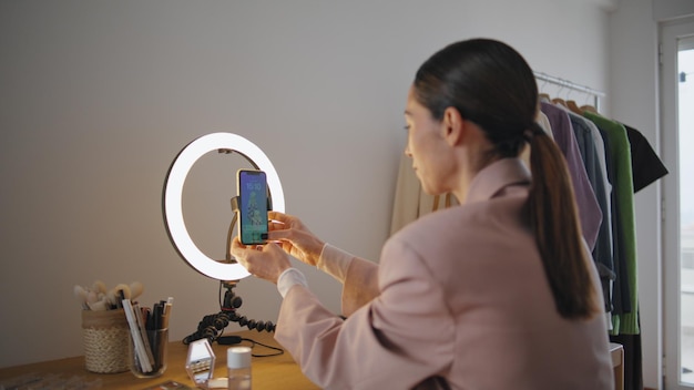 Mujer enfocada ajustando el teléfono inteligente en el lugar de trabajo mujer influyente presionando botones
