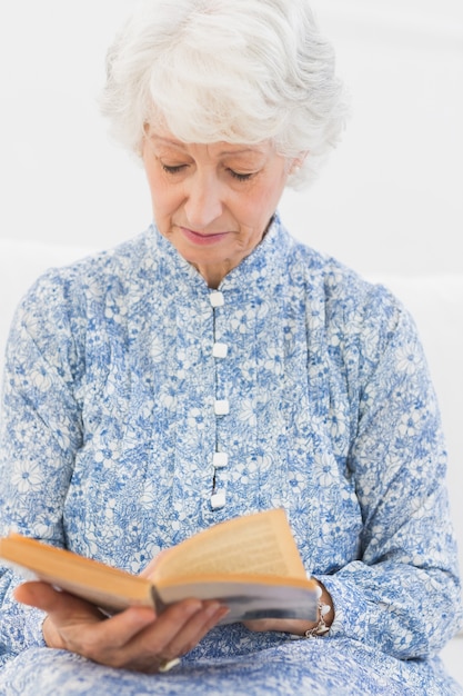 Mujer enfocada anciana leyendo una novela vieja