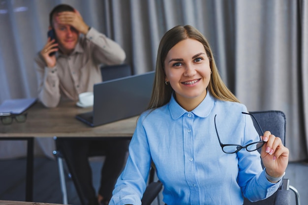 Mujer enfocada en ropa informal escribiendo en un netbook mientras trabaja en un nuevo proyecto mientras está sentada en un escritorio en un espacio de trabajo moderno Mujer de negocios con chaqueta y gafas Trabajo remoto