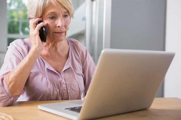 Mujer enfocada usando su computadora portátil y llamada