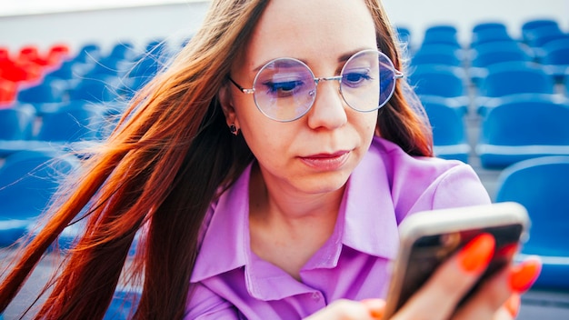 Mujer enfocada usando teléfono móvil en tribuna