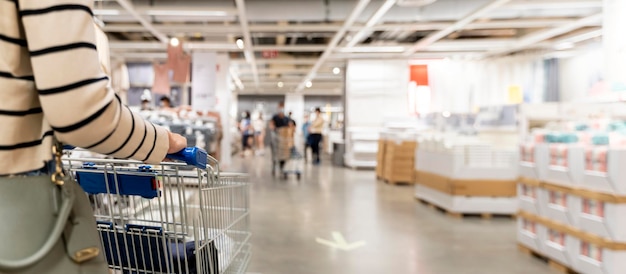 Mujer de enfoque suave con carrito de compras en la tienda de muebles en el almacén Muchos carritos de compras de metal grandes para los muebles de interior