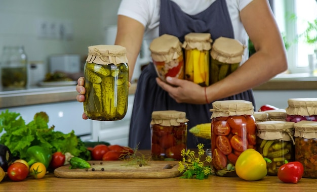 Mujer enlatando verduras en frascos en la cocina Foco selectivo