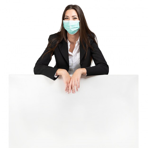 Mujer enmascarada apoyándose en un cartel, anuncio durante la pandemia de coronavirus, aislado en blanco