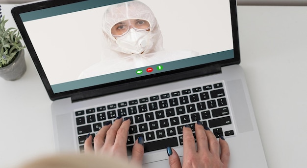 mujer enmascarada hablando en línea en una computadora portátil.