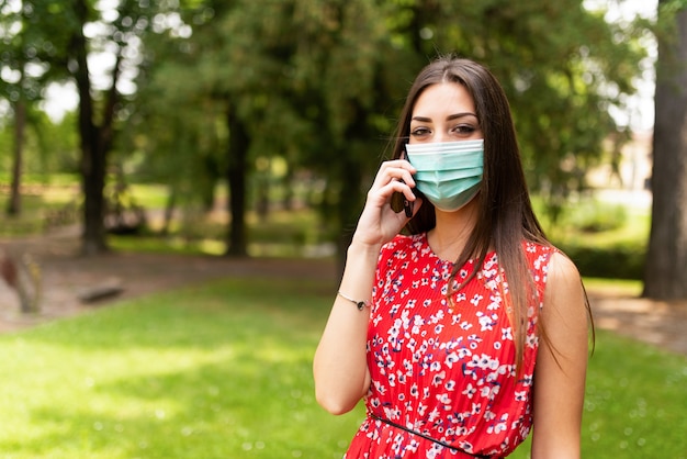 Foto mujer enmascarada hablando por teléfono