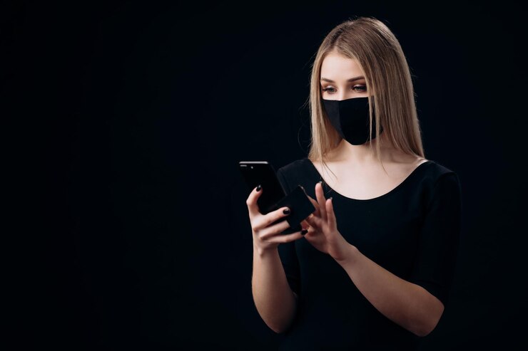 Mujer enmascarada con tarjeta de crédito y teléfono inteligente