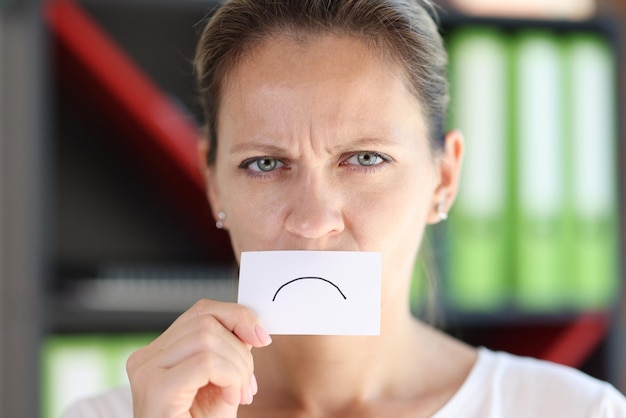 Mujer enojada sosteniendo una tarjeta con emoción negativa frente a su boca