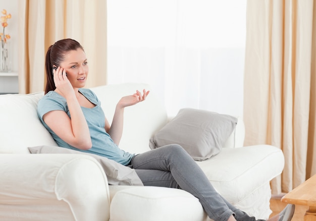 Mujer enojada en el teléfono mientras está sentado en un sofá