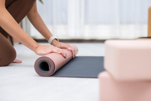 Mujer enrolla su alfombra de yoga después de la clase