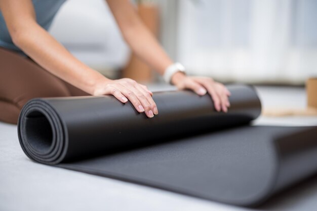 Mujer enrolla su alfombra de yoga después de la clase