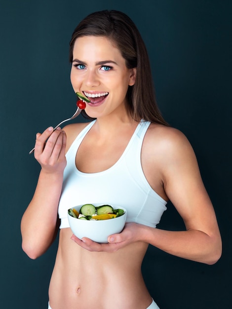 Mujer ensalada y comer retrato con fitness salud y nutrición de la comida con una sonrisa en el estudio entrenamiento feliz y modelo femenino con ejercicio y entrenamiento con dieta saludable alimentos y verduras