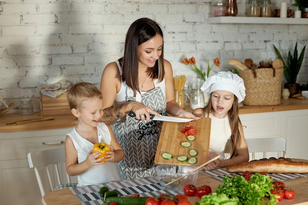 Una mujer le enseña a su hija a cocinar de su hijo