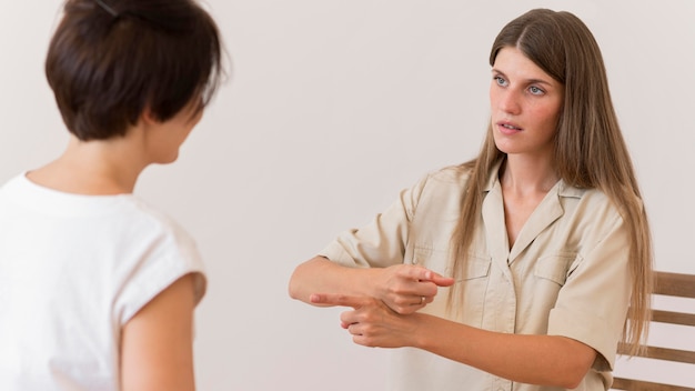 Foto mujer enseñando lenguaje de señas a otra persona