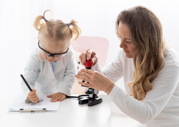 Foto mujer enseñando a un niño pequeño con gafas de seguridad sobre ciencia
