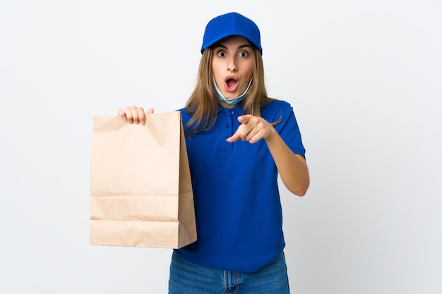 Mujer de entrega de alimentos sobre pared blanca sorprendida y apuntando al frente