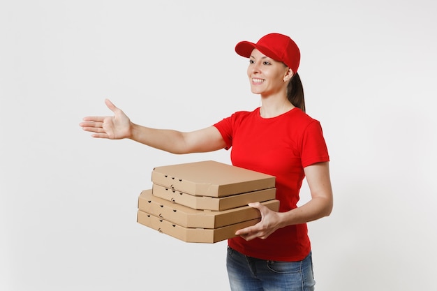 Mujer de entrega en gorra roja, camiseta dando cajas de pizza de pedido de comida aisladas sobre fondo blanco. Mensajero mujer de pie con la mano extendida para saludar, sosteniendo pizza italiana en caja plana de cartón.