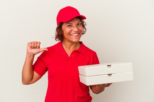 La mujer de entrega de mediana edad que toma pizzas aisladas sobre fondo blanco se siente orgullosa y segura de sí misma, ejemplo a seguir.