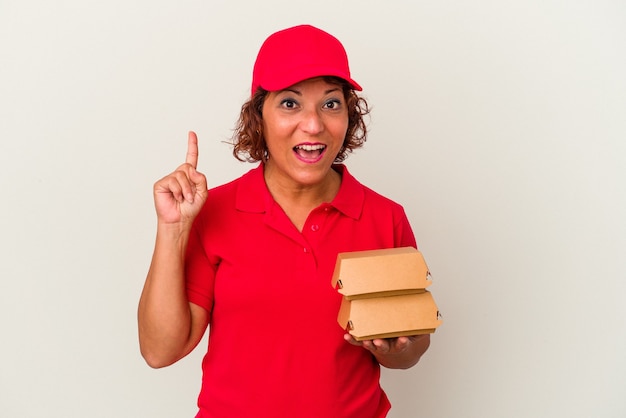 Mujer de entrega de mediana edad tomando burguers aislado sobre fondo blanco con una gran idea, concepto de creatividad.