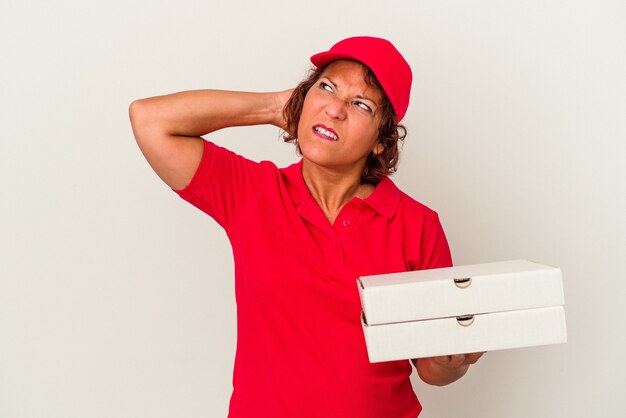 Mujer de entrega de mediana edad tomando pizzas aisladas sobre fondo blanco tocando la parte posterior de la cabeza, pensando y haciendo una elección.