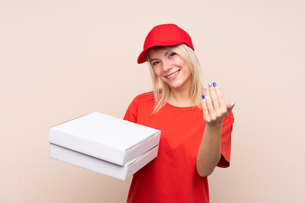 Mujer de entrega de pizza sosteniendo una pizza sobre pared aislada invitando a venir con la mano. Feliz de que hayas venido