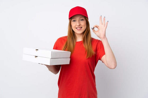 Mujer de entrega de pizza sosteniendo una pizza sobre la pared rosa que muestra un cartel con los dedos