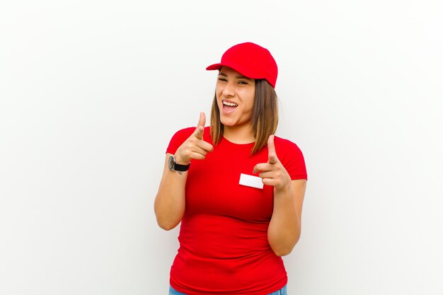 Foto mujer de entrega sonriendo con una actitud positiva, exitosa y feliz apuntando, haciendo el signo de pistola con las manos