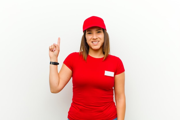 Mujer de entrega sonriendo alegre y alegremente, apuntando hacia arriba con una mano para copiar espacio