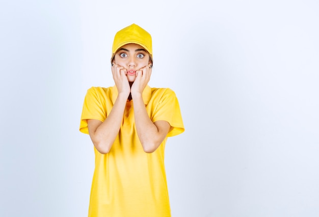 Mujer de entrega en uniforme amarillo de pie y posando.