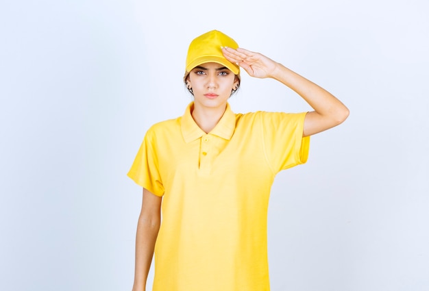 Mujer de entrega en uniforme amarillo de pie y saludando.