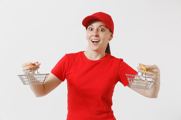 Mujer de entrega en uniforme rojo aislado sobre fondo blanco. Mensajero femenino o distribuidor en gorra, camiseta, jeans con canasta de metal para ir de compras en el supermercado. Copie el espacio para publicidad.