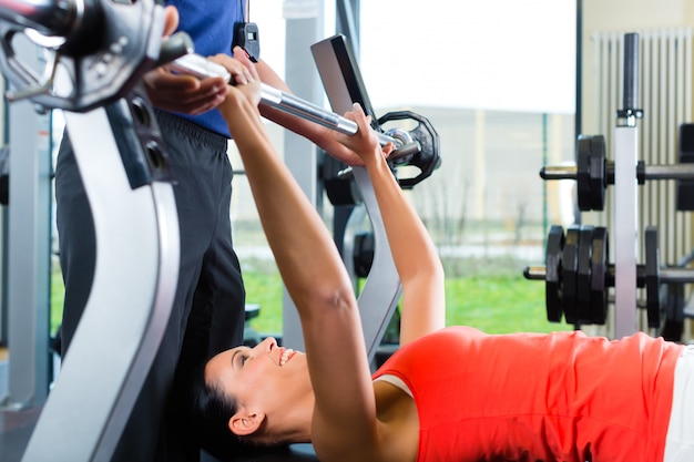 mujer y entrenador personal en gimnasio