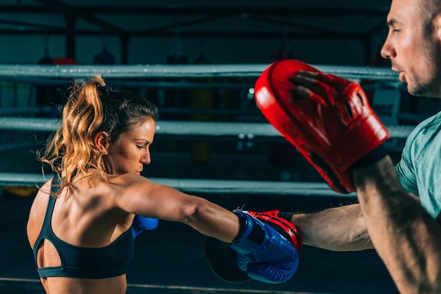 Mujer en entrenamiento de boxeo con entrenador