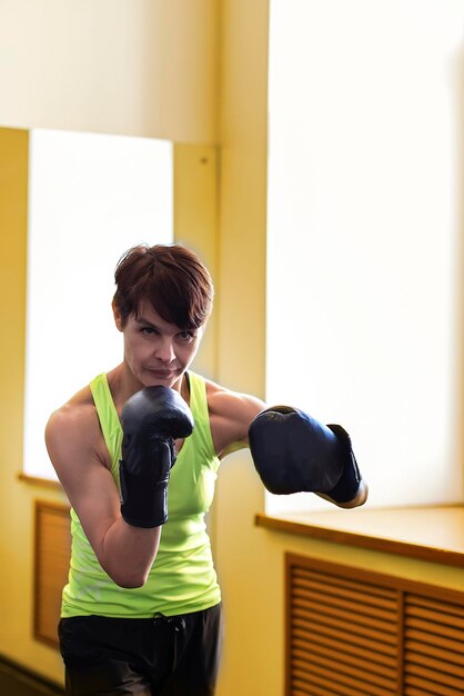 Mujer de entrenamiento de boxeo en saco de boxeo de gimnasio