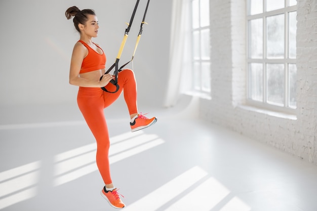 Mujer entrenando con correas de fitness TRX