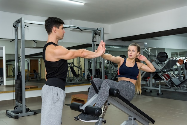 Mujer entrenando en gimnasio con entrenador personal