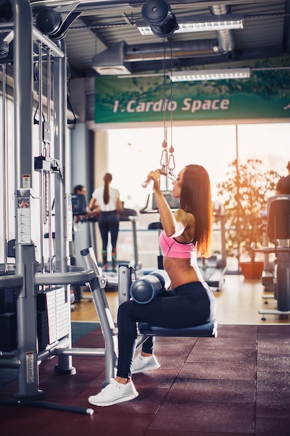 Mujer entrenando con máquina de levantamiento de pesas