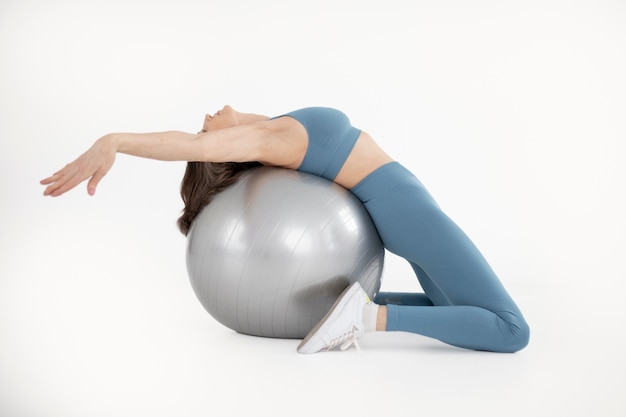 Mujer entrenando con pelota de gimnasia tiro completo