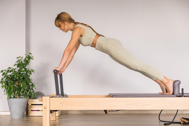 Mujer entrenando pilates en la cama reformer máquina de estudio de pilates reformer para ejercicios de fitness en g