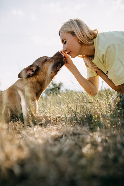 Mujer entrenando a su perro dando un regalo al aire libre en un campo